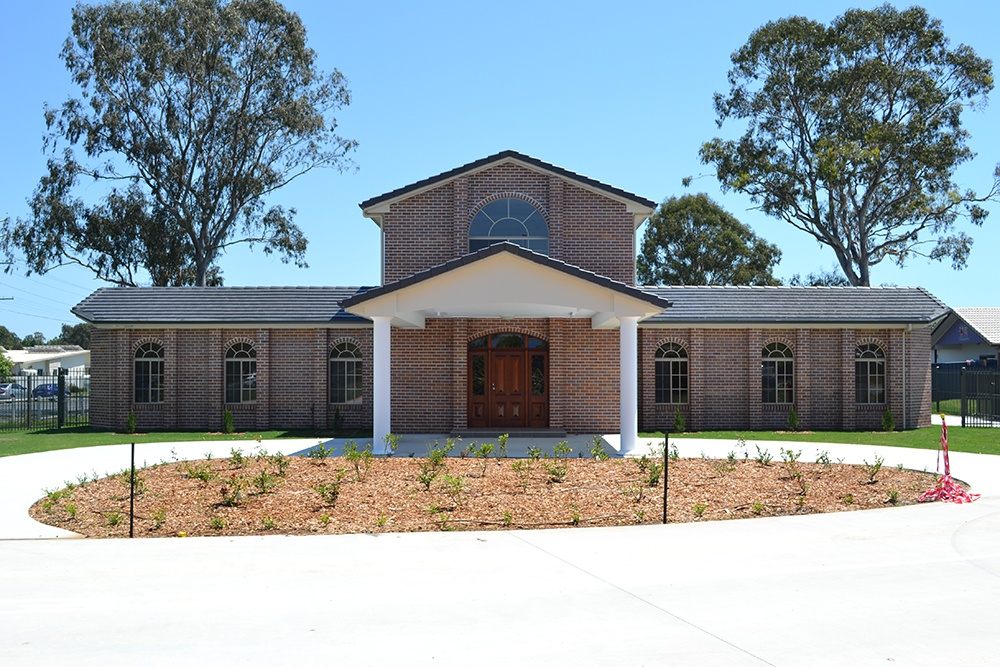 Two level red brick Bishop’s Manse with drive-up entrance and arch windows at Greek Orthodox Archdiocese.